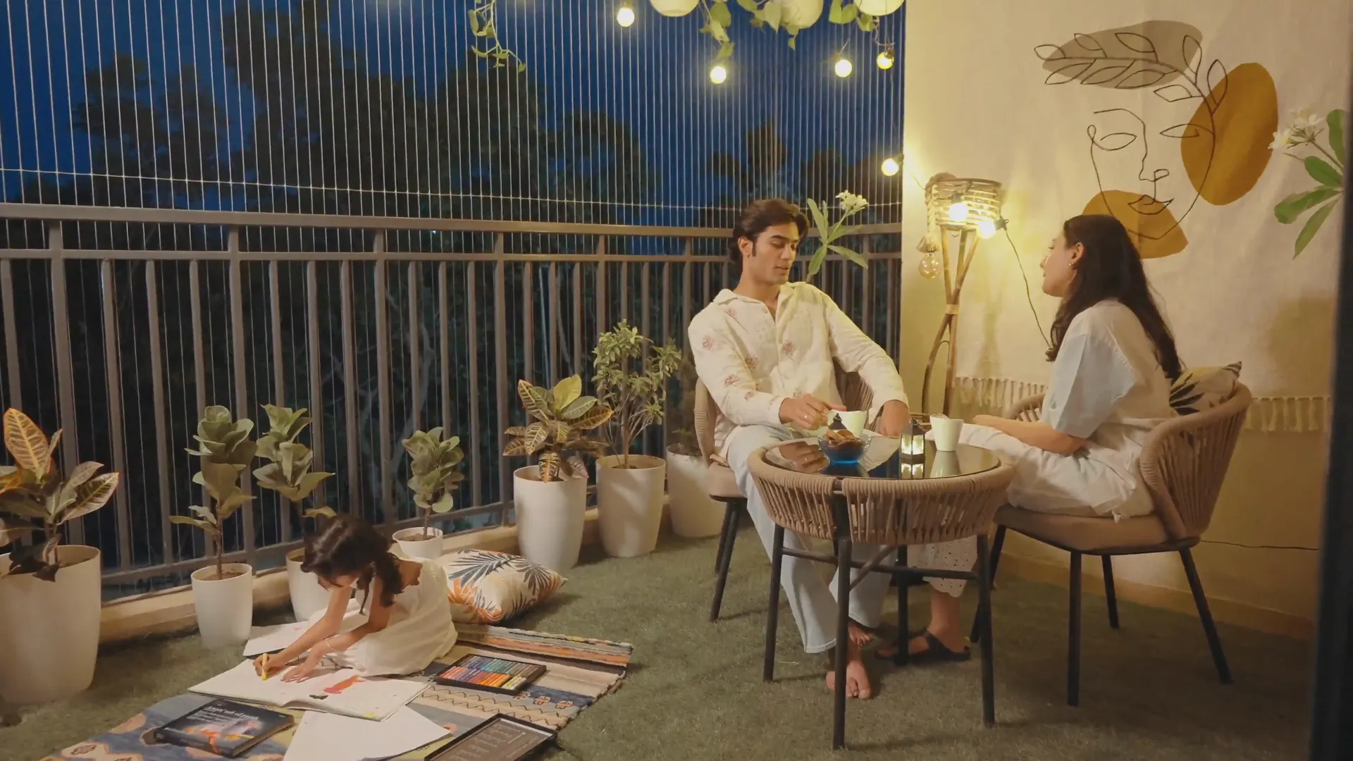 A family spending the evening on their balcony under string lights